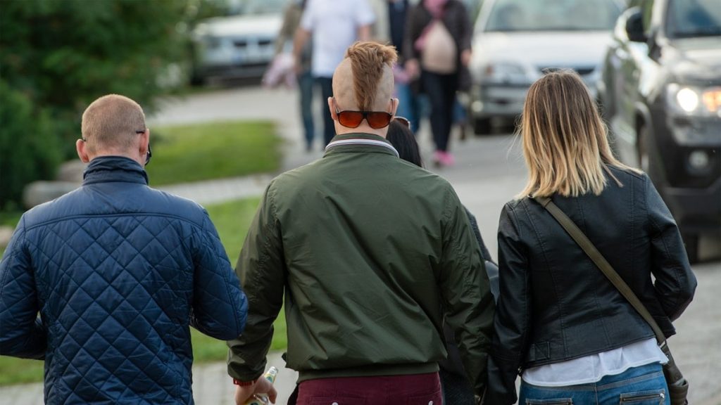 A stylish group of friends with alternative fashion and a mohawk hairstyle walking through the streets of Tallinn on a summer evening.